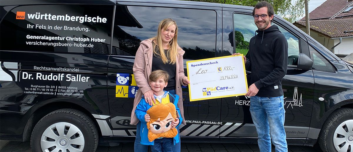 PädCare vor dem Firmenauto mit einem Kind und einen Spendencheck